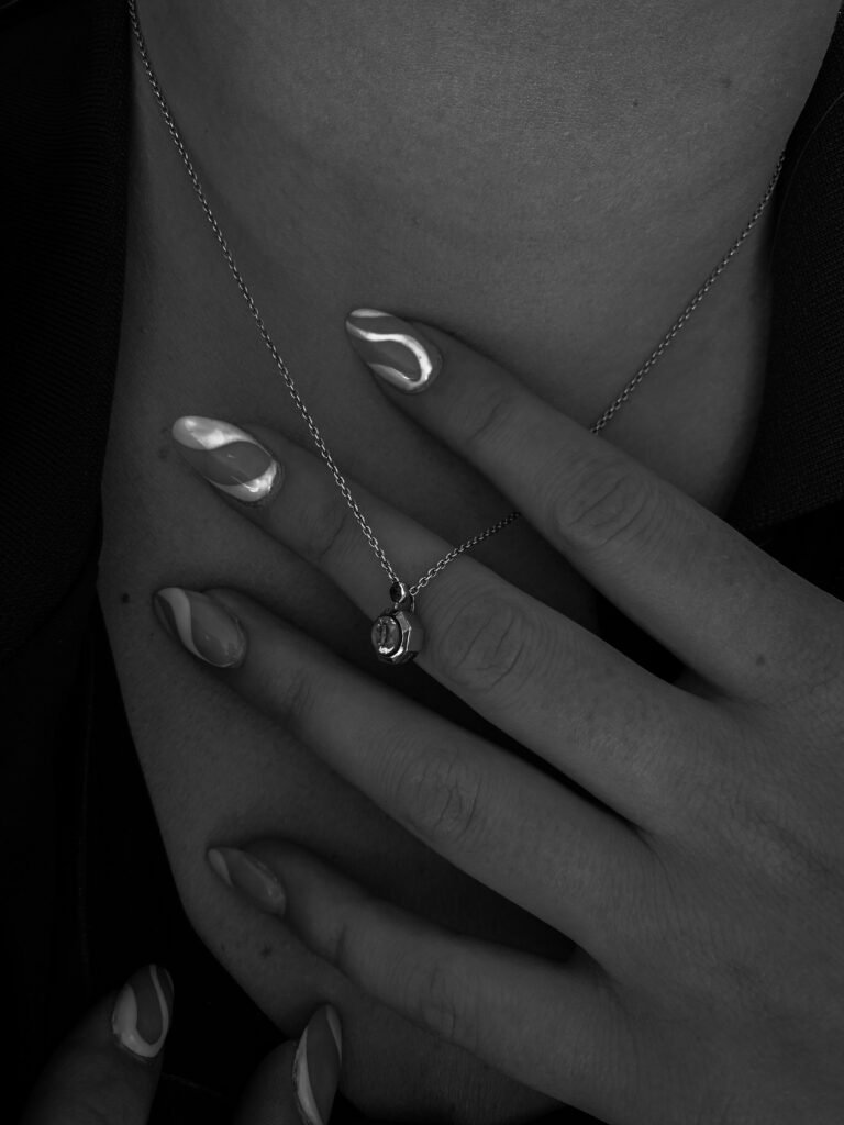 Stylish black and white close-up of a hand holding a silver pendant.