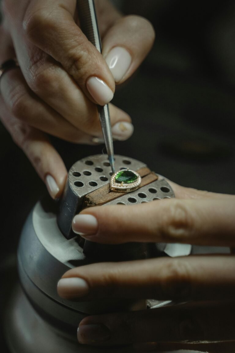 A skilled jeweler carefully crafting an emerald ring using a tweezer, showcasing craftsmanship.